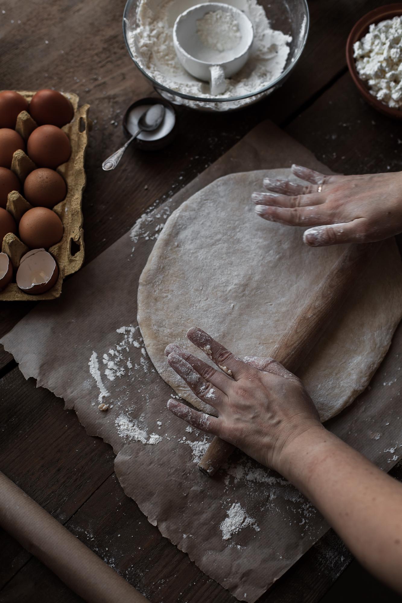 Close-up of hands kneading dough on floured board